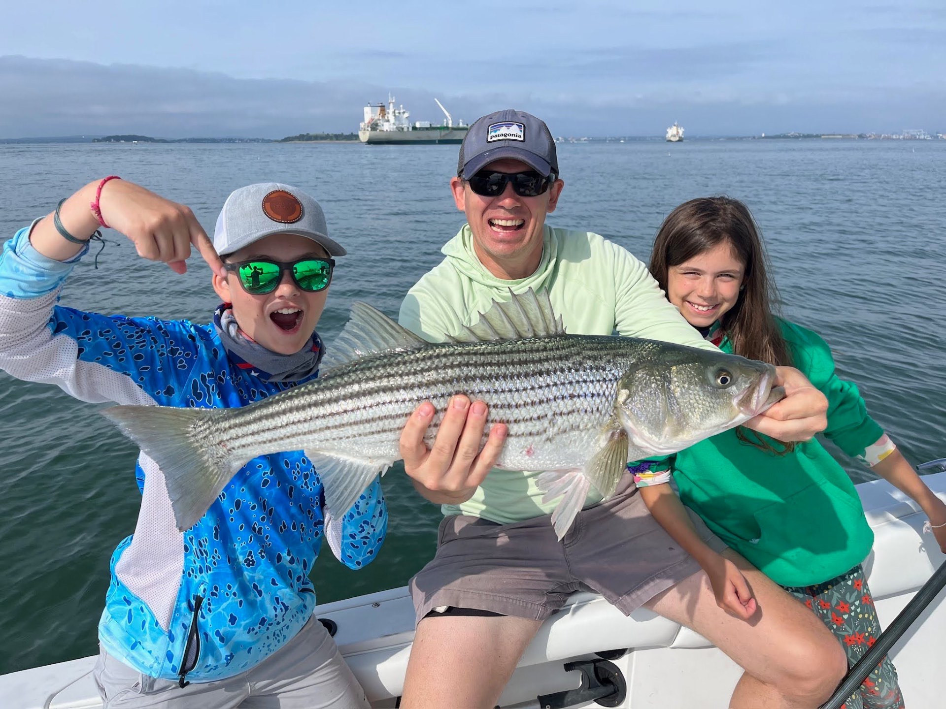 Rob and the kids holding a big striped bass