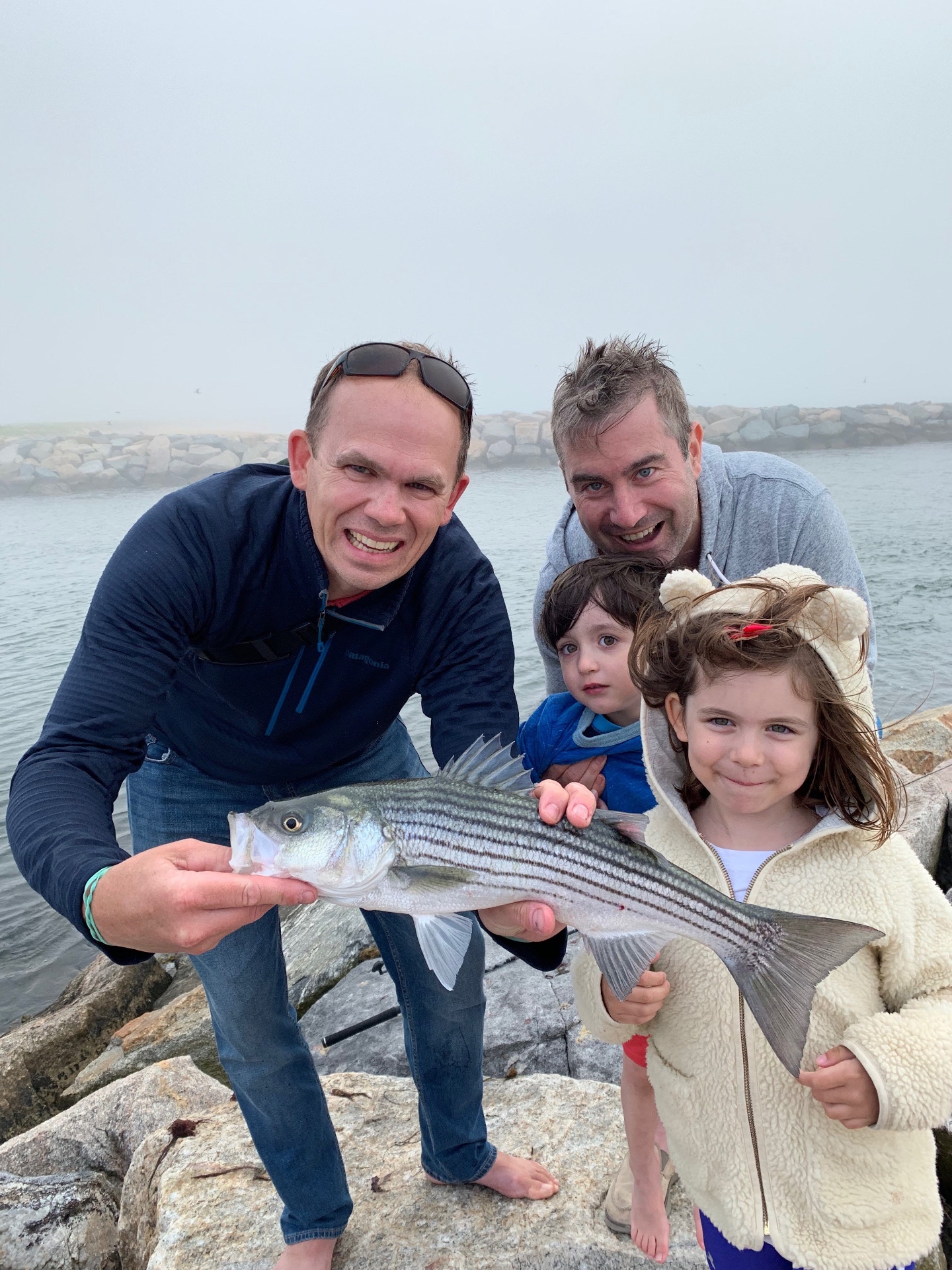Rob, family, and a striper on the jetty in the fog